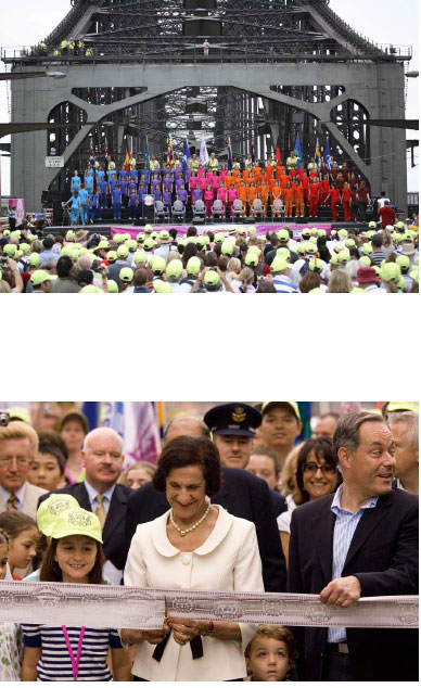 ECHOING THE RIBBON CUTTING OF 1932. The Governor of NSW, Her Excellency Professor Marie Bashir, cuts the ribbon using the actual scissors used by Jack Lang in 1932. Triggering the Our Bridge overture a specially commissioned work composed by Elana Kats-Chernin, seven sound pods spaning the road between the pylons come to life each representing a decade, these were emotive clearly defined sound environments that combined a collage of voice and music from each period. All air and water activity around the harbour commences as does the bridge walk that lasted the entire day and well into the night, each person who walks receives a specially design cap, the day walkers cap is fluoro yellow a wink to the safely and utilitarian nature of the bridge while the night cap is fl uoro orange and has a super bright white LED light on the front of each cap.